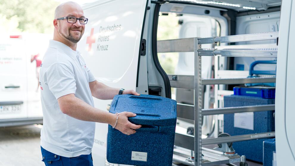 Versorgung von Patienten mit Blutspenden: Mitarbeiter lädt Transportboxen mit Blutspenden ein