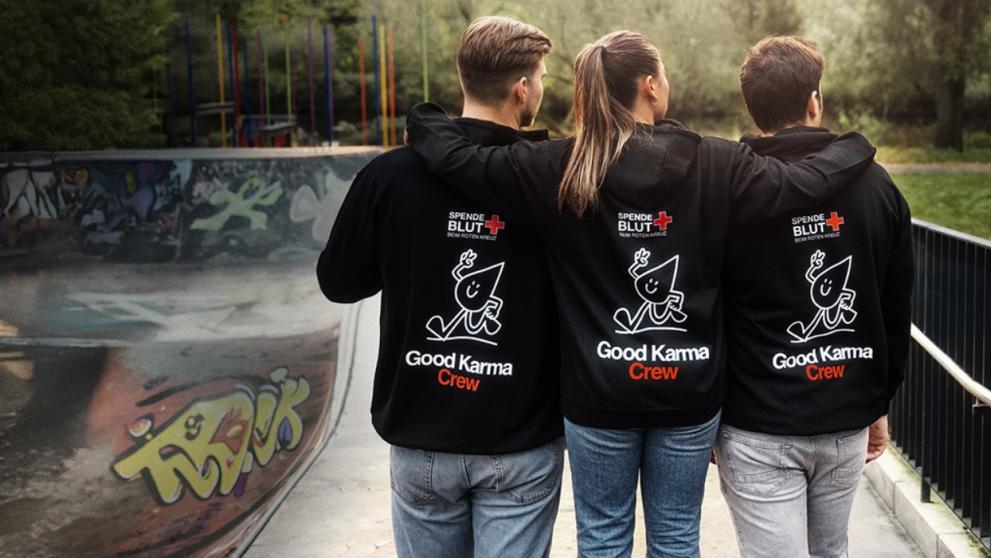 Drei Menschen umarmen sich und tragen die Good Karma Hoodies