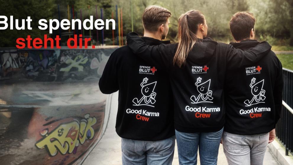 Drei Menschen umarmen sich und tragen die Good Karma Hoodies