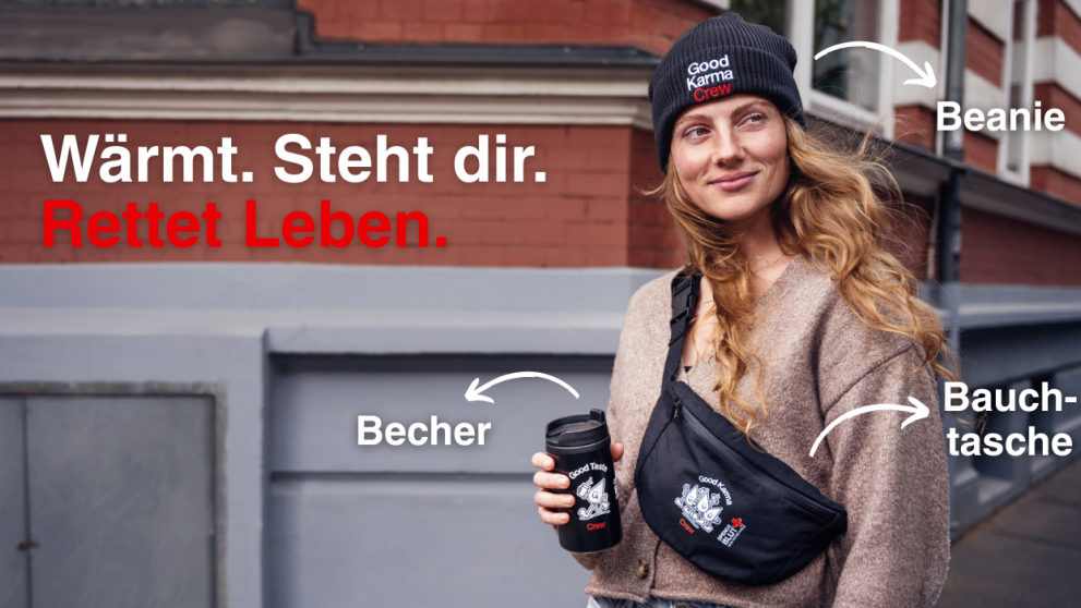 Eine Frau hält einen Kaffeebecher und trägt dazu eine Beanie und eine Bauchtasche.