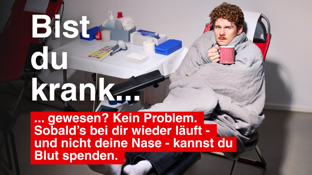 Ein Mann hält eine Tasse in der Hand und liegt auf der Blutspendeliege.