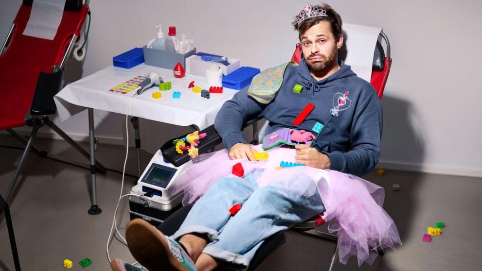 Ein Mann hat Spielzeug um sich herum und liegt auf der Spendeliege.