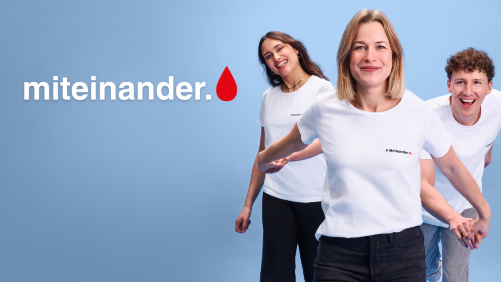 Drei Freunde, die sich an den Händen fassen. Alle mit dem miteinander-Shirt an. 