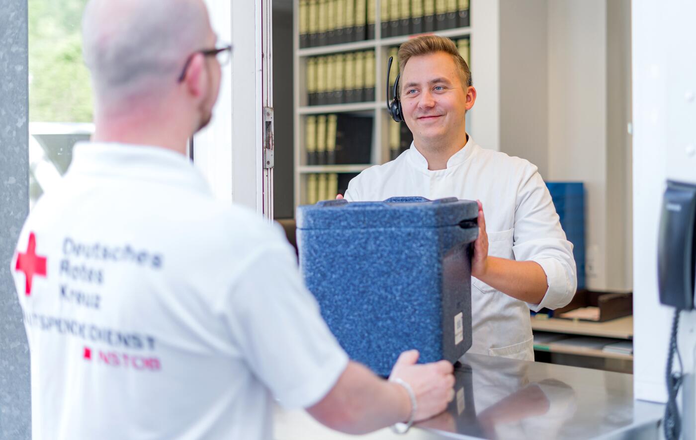 Blutspenden auf dem Weg zum Patienten: Übergabe einer Box mit Blutspenden fertig zum Transport