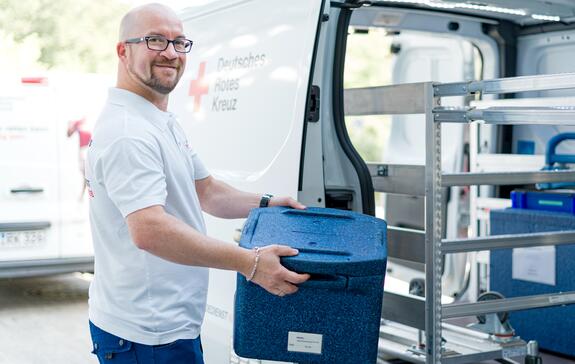 Versorgung von Patienten mit Blutspenden: Mitarbeiter lädt Transportboxen mit Blutspenden ein