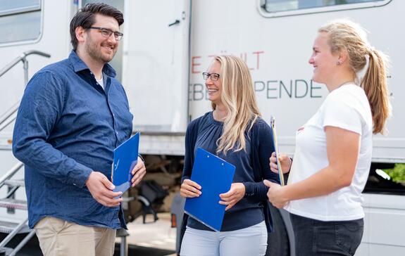 Freunde mit zur Blutspende nehmen: 3 Spender stehen vor einem Blutspendemobil