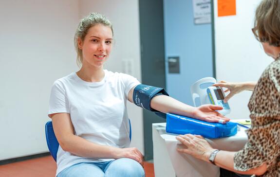 Junge Frau wird vor der Blutspende untersucht und führt ein Gespräch mit ihrem Arzt
