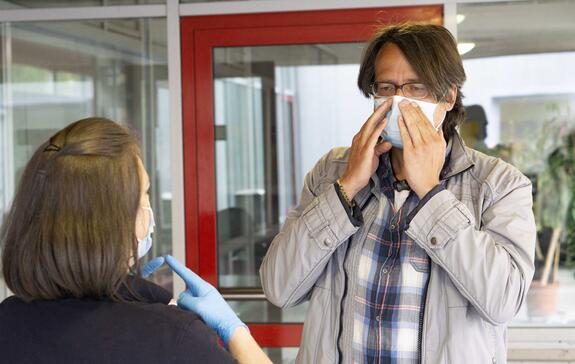 Blutspender erhält vor Betreten des Spendelokals eine Mund-Nasen-Maske