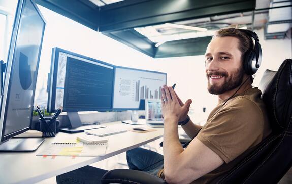 Ein Mitarbeiter aus IT sitzt an seinem Arbeitsplatz vor seinem Computer