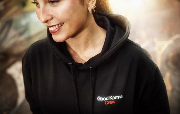 Eine Frau mit schwarzem Hoodie ist in Nahaufnahme zu sehen. Auf dem Hoodie steht "Good Karma Crew"