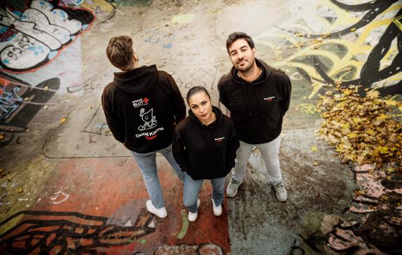 Drei Personen tragen einen Blutspende-Hoodie und stehen zusammen