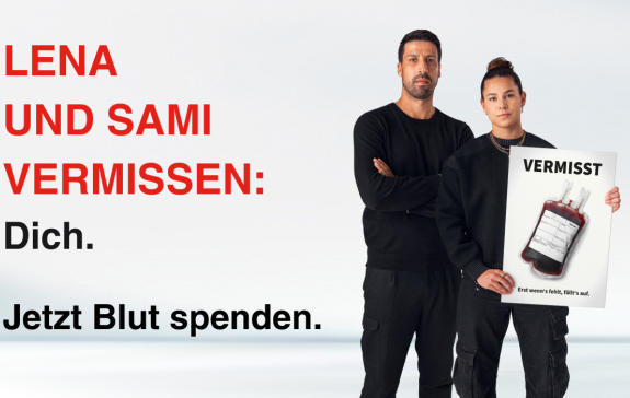 Lena und Sami halten ein Schild mit einer fehlenden Blutkonserve hoch. Auf dem Bild steht: Lena und Sami vermissen: Dich. Jetzt Blut spenden.
