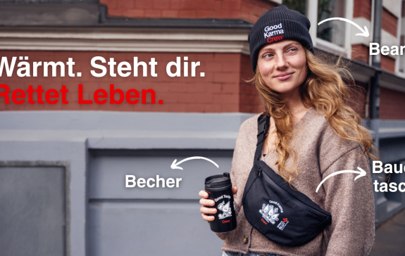 Eine Frau hält einen Kaffeebecher und trägt dazu eine Beanie und eine Bauchtasche.