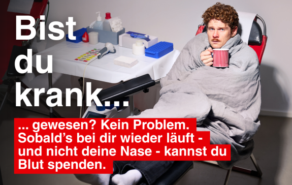 Ein Mann hält eine Tasse in der Hand und liegt auf der Blutspendeliege.